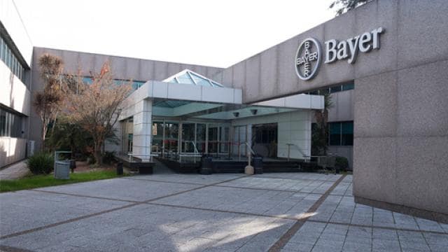 Exterior de un edificio de oficinas de Bayer con una entrada de vidrio y el logotipo de Bayer en un lugar destacado.