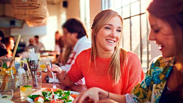 Personas disfrutando de una comida juntas en un restaurante luminoso y concurrido.