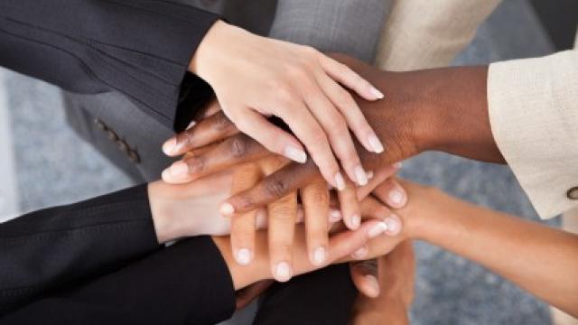 Un grupo de manos diversas unidas en el centro, simbolizando la unidad y el trabajo en equipo.