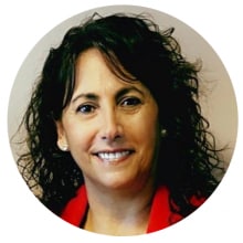 Mujer sonriente con cabello rizado, con una chaqueta roja, en un marco circular.